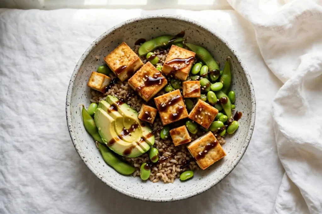 Edamame and tofu brown rice bowl with avocado and sesame on a ceramic plate — fully plant-based high protein meal prep