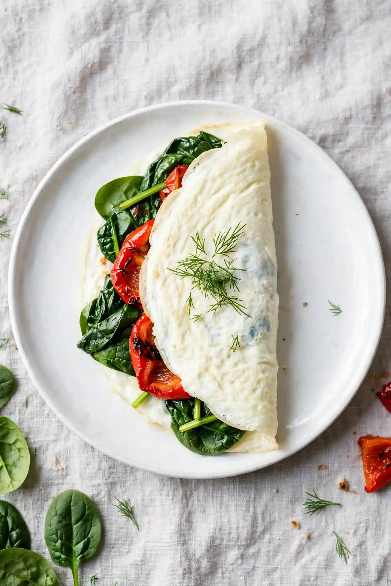 Egg white omelette with spinach and roasted red pepper on a white plate — light egg white omelette recipe