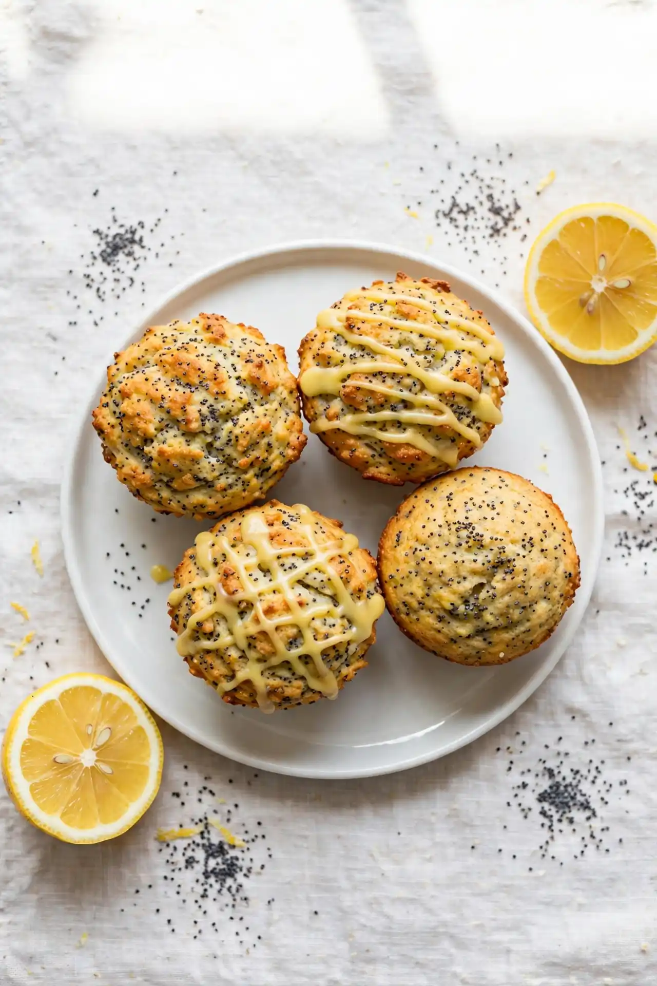 Lemon poppy seed protein muffins with lemon glaze drizzle on a white plate with fresh lemon — lemon poppy seed protein muffins