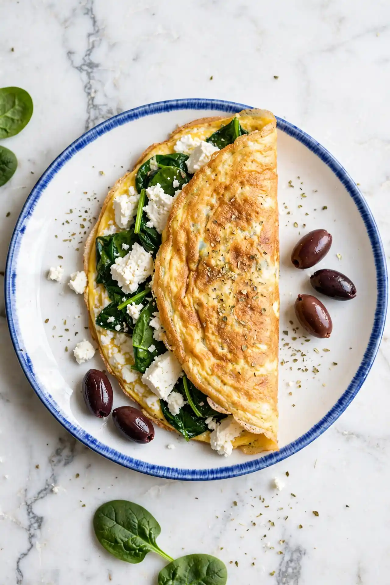 Greek omelette with feta cheese, olives, and spinach on a ceramic plate — Greek-style omelette recipe